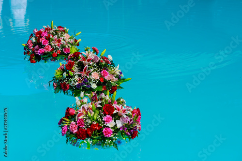 Fototapeta Naklejka Na Ścianę i Meble -  Fresh garden roses on the blue water of a swimming pool on a warm summer day.