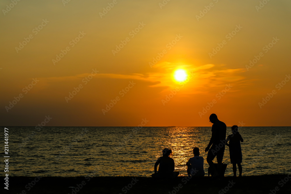 silhouette family play with one dog on beach sunset