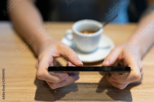 Woman using a mobile phone as she drinks coffee