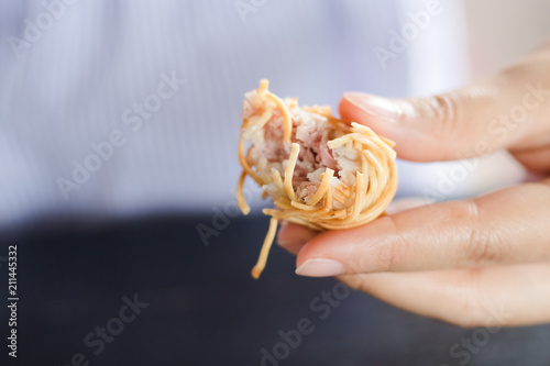 Konstfotografi Left hand of woman holding moo sarong (Thai appetizer)