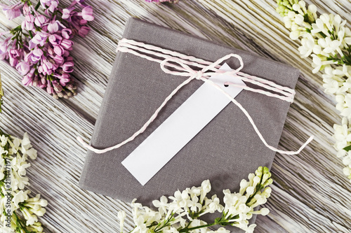Fotografi Gift box with a place for signature or wishes decorated with a twig and lilac on old wooden background