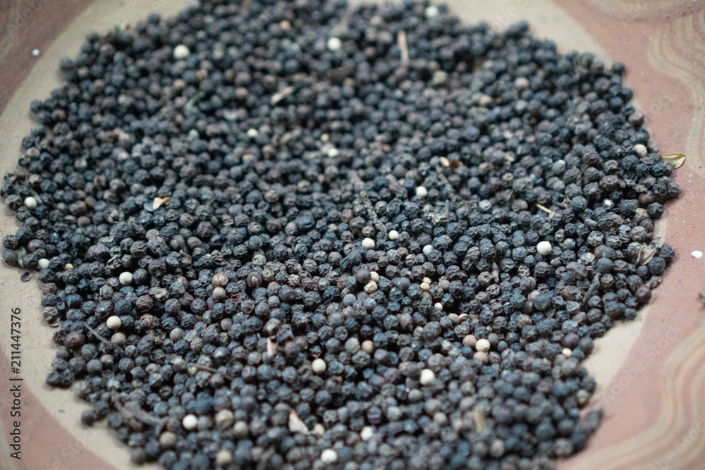 Closeup dried black pepper on the rustic clay brown plate Closeup dried black pepper on the rustic clay brown plate