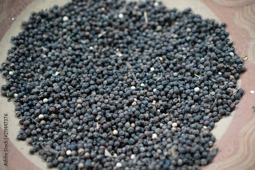 Closeup dried black pepper on the rustic clay brown plate