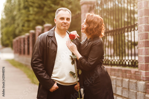 a man and a woman with a red rose in the outdoors