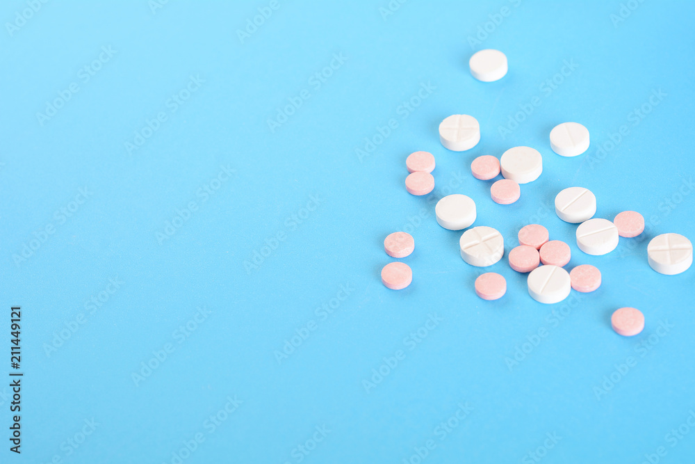 Pile of white pills on light blue background
