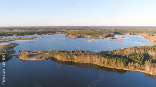 Fototapeta Naklejka Na Ścianę i Meble -  Picturesque landscape with forest and pond at sunset. Beautiful sunlight in spring. Aerial view photo.