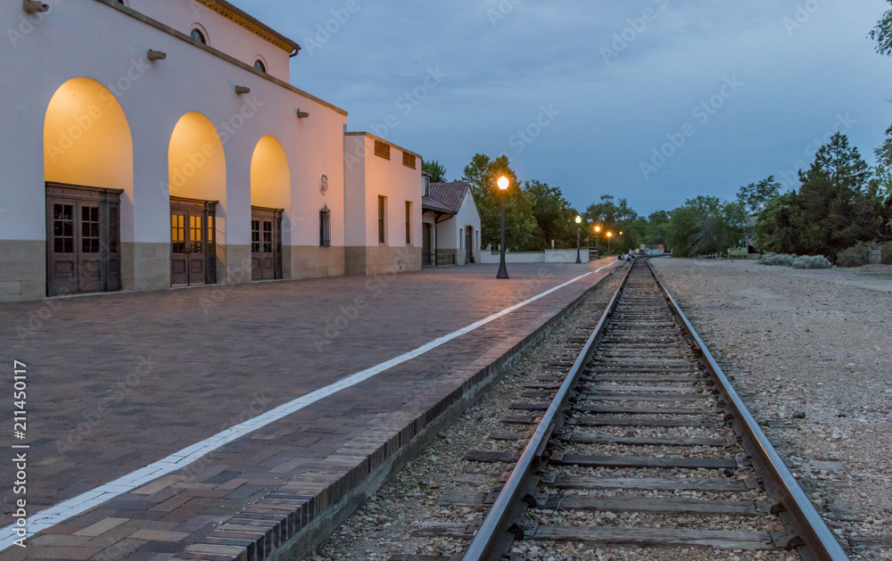 Fototapeta premium Train tracks at Boise Depot at sunset on a summer evening. Landmark railroad train depot with bell tower in Boise, Idaho. 