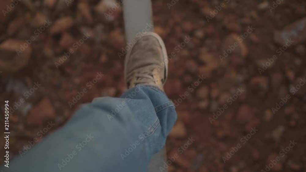 A person walking on a slim beam under a bridge with a substantial drop. A person walking on a slim beam under a bridge with a substantial drop.