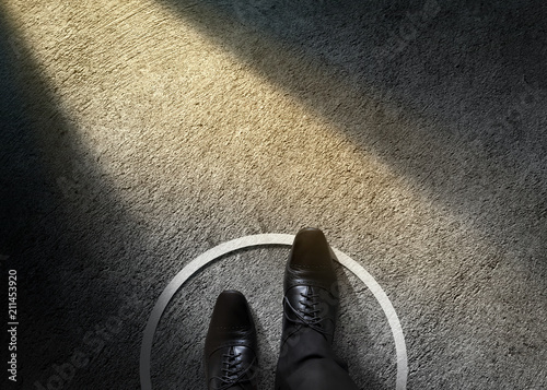 Comfort Zone Concept. Businessman with Formal Shoes Steps over Circle Line to Outside the White Bound. Top View, Dark Tone, Light Shading on Cement Floor photo