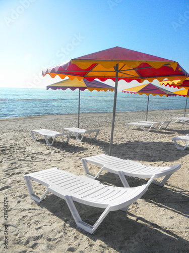two sun loungers under an umbrella against the background of the sea