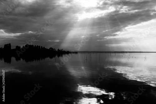 Perfectly symmetric and spectacular view of a lake, with clouds, sky and sun rays reflecting on water