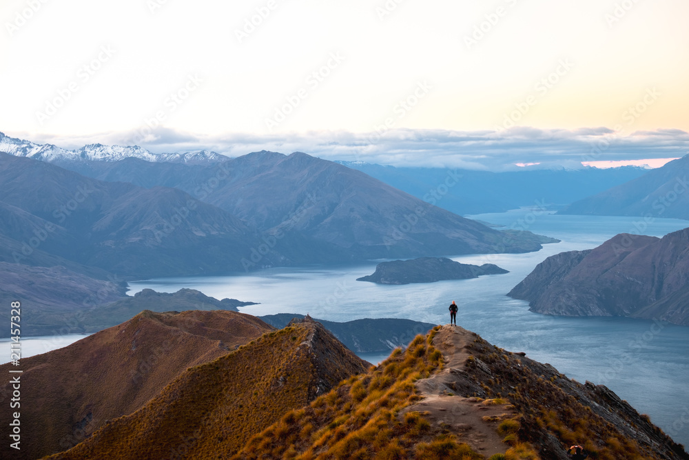 A woman looking at the beautiful landscape of the mountains and Lake Wanaka. Roys Peak Track, South Island, New Zealand.