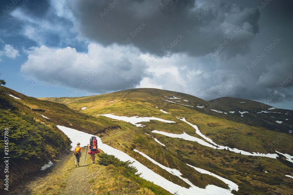 Fototapeta premium Family hikers walking by the road in a spring mountains
