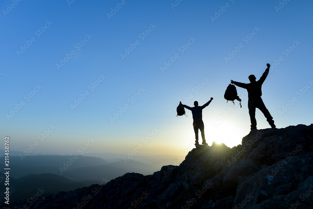 Hiker with backpack standing on top of a mountain with raised hands and ...