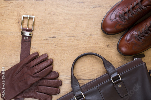 Brown leather men's accessories on wooden desk