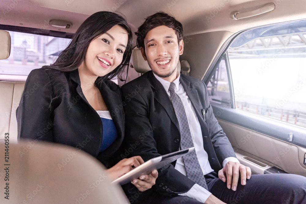 Happy handsome business man and Business woman sitting in luxury limousine car, working on laptop computer, Works anytime and anywhere concept. Happy handsome business man and Business woman sitting in luxury limousine car, working on laptop computer, Works anytime and anywhere concept.