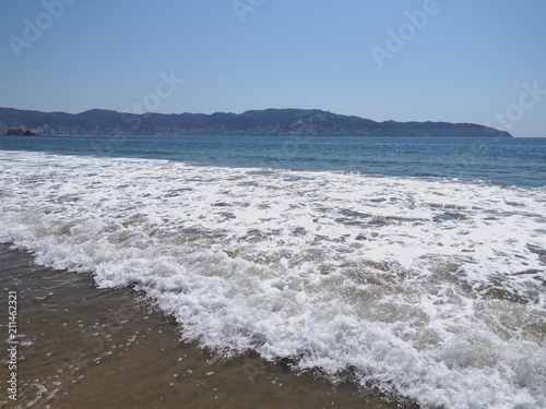 Beauty view of sandy beach at bay of ACAPULCO city in Mexico with tourists and white waves of Pacific Ocean