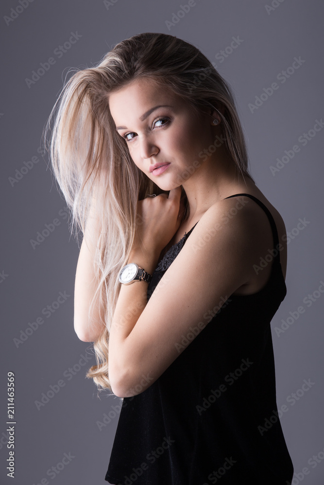 Naklejka premium Close up studio portrait of a pretty blonde woman, smiling and looking at the camera