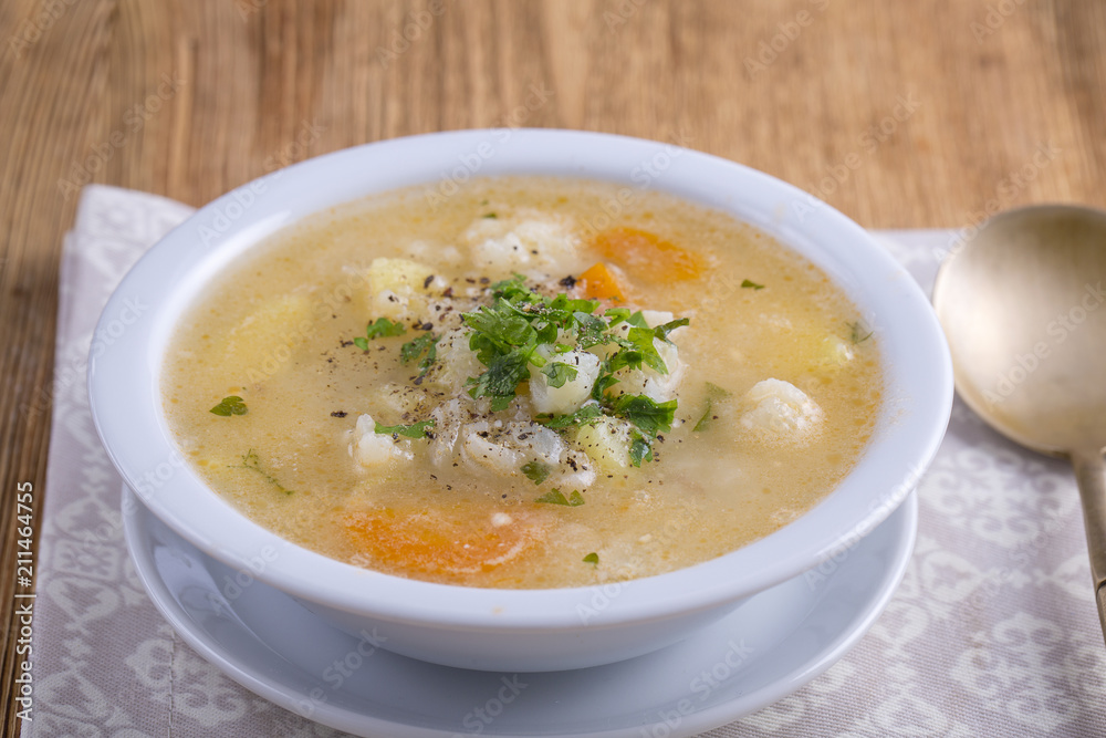 Fresh vegetable soup made of carrot, potato, cauliflower, parsley and rice in white plate, Fresh vegetable soup made of carrot, potato, cauliflower, parsley and rice in white plate,