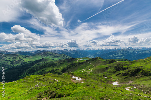 Wanderwege zwischen den grünen Wiesen in der Ferne, schneebedeckten Gipfeln