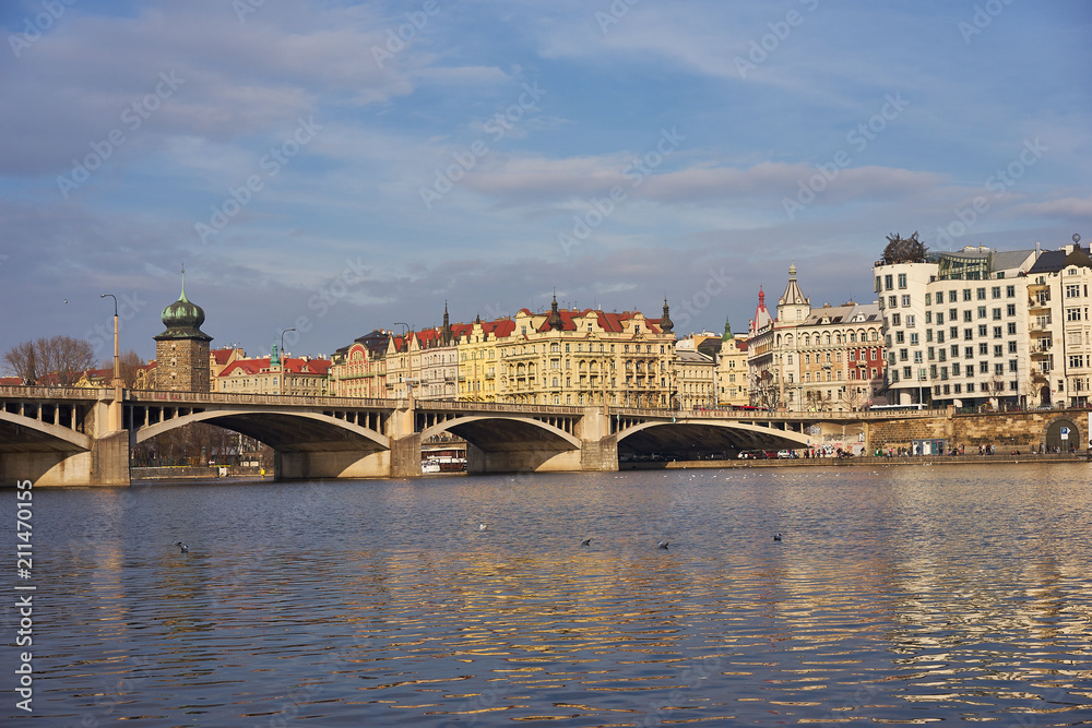 Fototapeta premium Landmark Picture of the Prague river side with bridge and buildings on the bank of Vltava river with famous dancing house, Picture is taken in sunny spring day. 