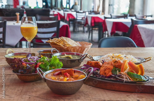 Indisches Essen mit Nan, Masal, Salat, Chicken Tandoori,  Tikka, Spinat, Basmati schön angerichtet in einem Restaurant auf einem Holztisch serviert photo