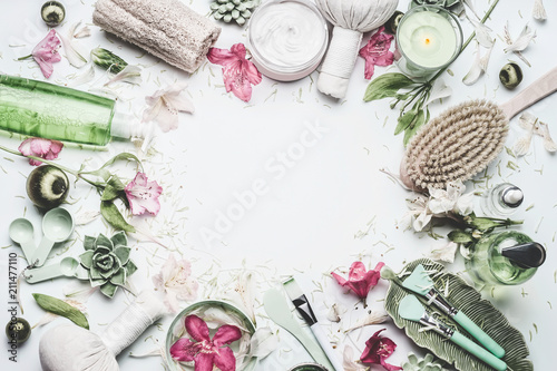 Spa and wellness background with  flowers, skin cosmetic products and others body care and massage accessories on white background, top view, frame with copy space