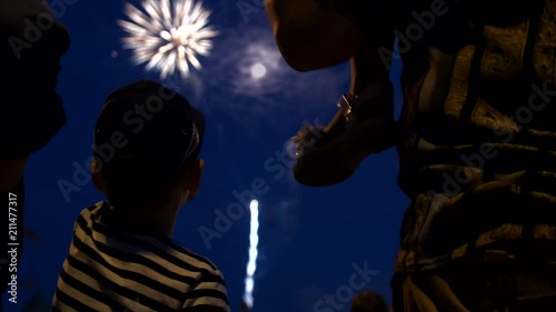 The child sits on the daddy's neck and looks at the firework