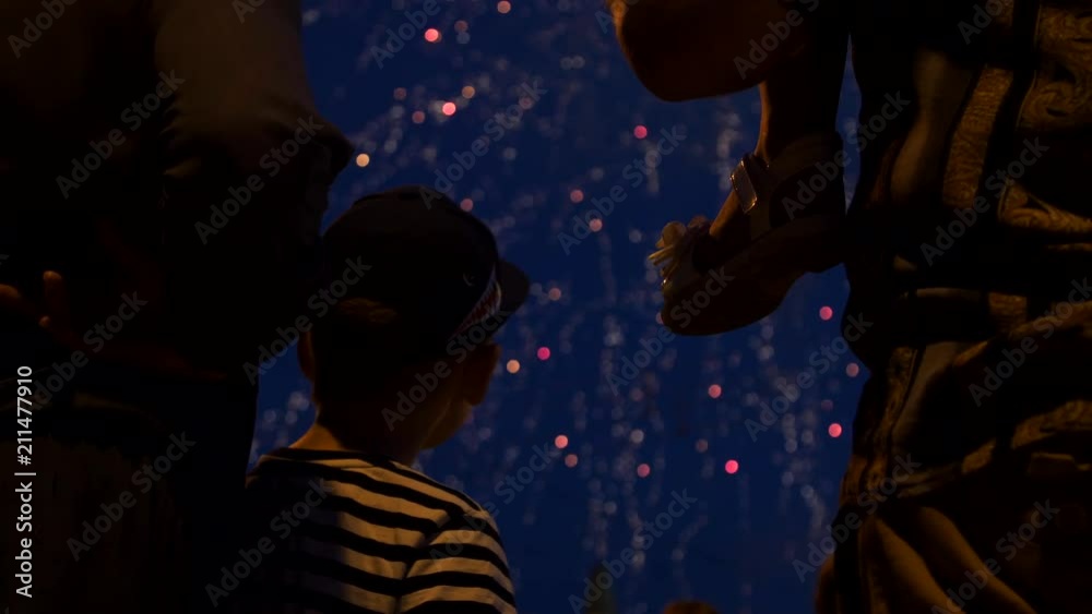 The child sits on the daddy's neck and looks at the firework The child sits on the daddy's neck and looks at the firework