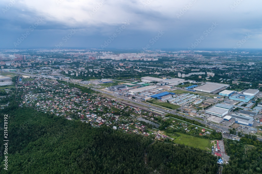 Aerial view of wheat fields, meadow, forest andindustrial warehouses in rural Russia.