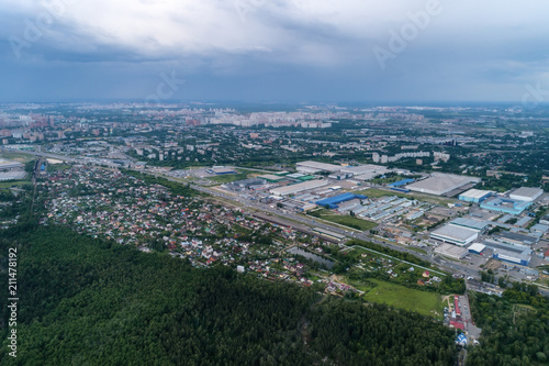 Aerial view of wheat fields, meadow, forest andindustrial warehouses in rural Russia.