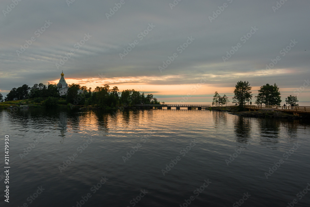 Sunset over the St. Nicholas monastery and the water surface of lake Ladoga. Valaam is a cozy and quiet piece of land, the rocky shores of which rise above the lush waters of lake Ladoga