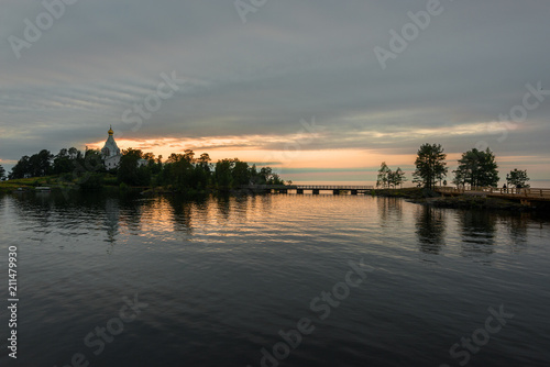 Sunset over the St. Nicholas monastery and the water surface of lake Ladoga. Valaam is a cozy and quiet piece of land, the rocky shores of which rise above the lush waters of lake Ladoga
