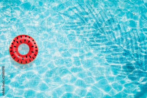 Pool float, ring floating in a refreshing blue swimming pool with palm tree leaf shadows in water