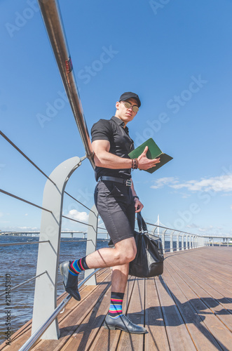 a student in a shirt and glasses reading a book in the city Park © dmitrypk