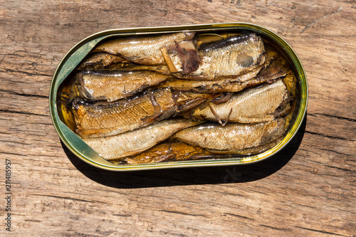 Open tin can of sprats on rustic wooden table