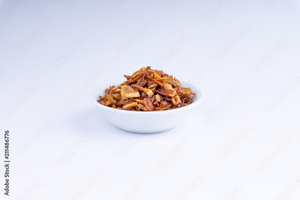 Deep fried shallots crisp / fried crispy onion flakes (bawang goreng) in white bowl over wooden background. Deep fried shallots crisp / fried crispy onion flakes (bawang goreng) in white bowl over wooden background.