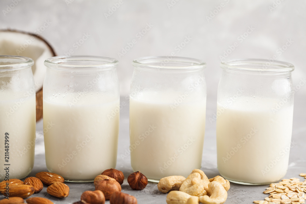 Vegan alternative nut milk in glass bottles on gray background. Healthy vegan food concept. Vegan alternative nut milk in glass bottles on gray background. Healthy vegan food concept.