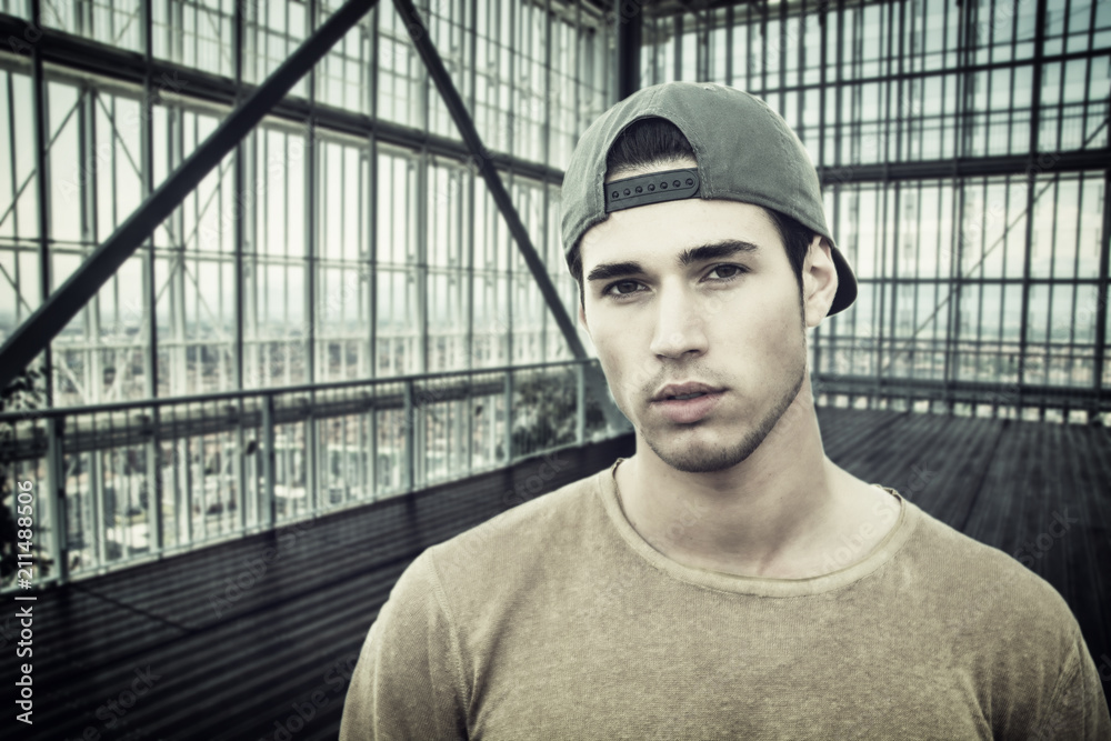 Handsome serious man standing inside modern building next to big window, looking out Handsome serious man standing inside modern building next to big window, looking out