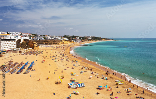 Portugal. Algarve. Top view of the beautiful sandy beaches near the old town of Albufeira and the silhouettes of people vacationing by the sea coast on a sunny day © Katvic