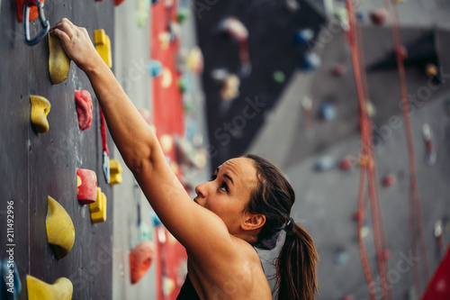 Sporty young woman training in a colorful climbing gym. Free climber girl climbing up indoor