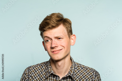 doubtful man raising eyebrow ironically. stuck up mockery. portrait of a young guy on light background. emotion facial expression. feelings and people reaction. photo