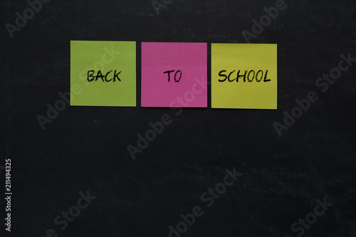 Letras de vuelta a la escuela escritas en notas de colores en una pizarra negra 