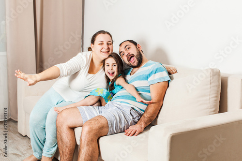 Happy family sitting together on a sofa in the living room. © oksix