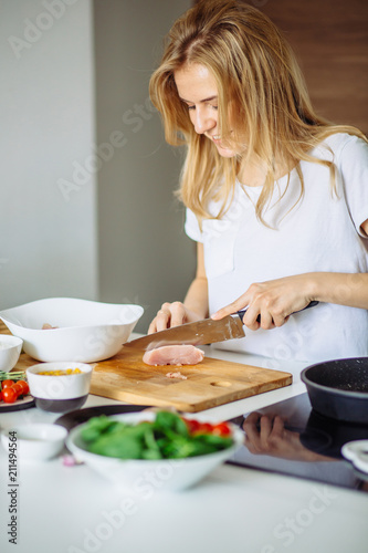 Fotografie Woman cutting chicken meat for being marinated later