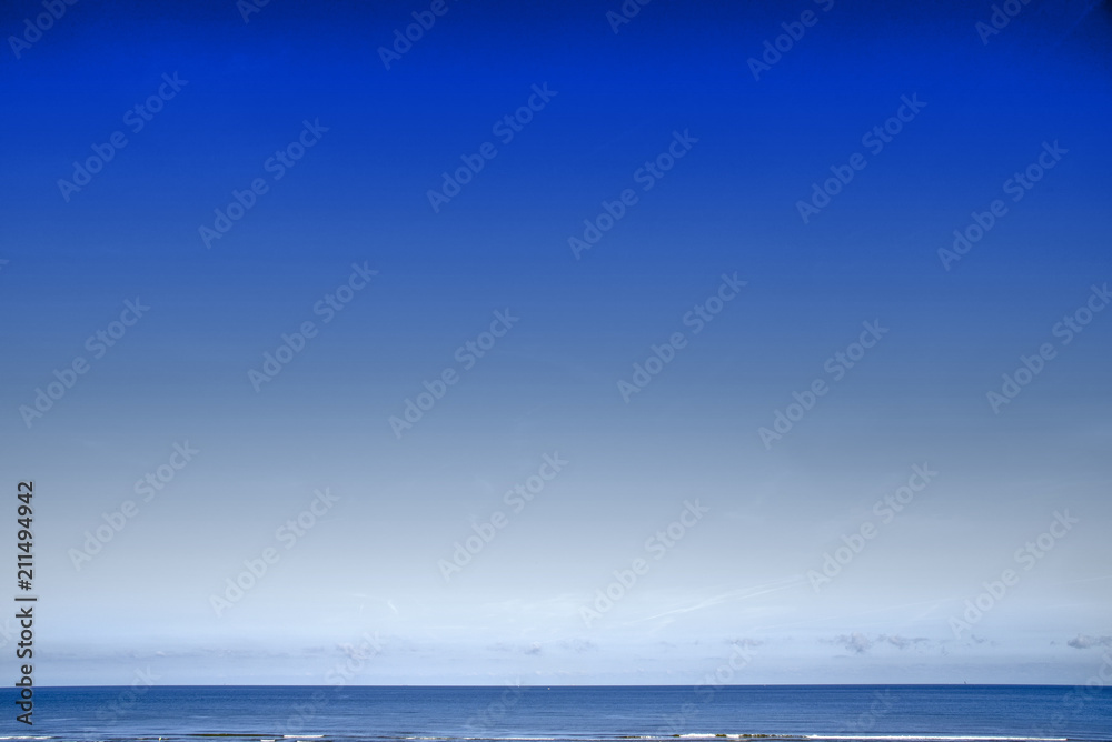 Deep blue color sky gradient background of a seascape with flat horizon and few calm waves