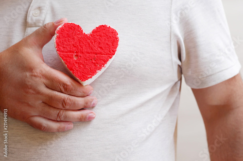 hand holding shabby heart figure before chest, heart care concept