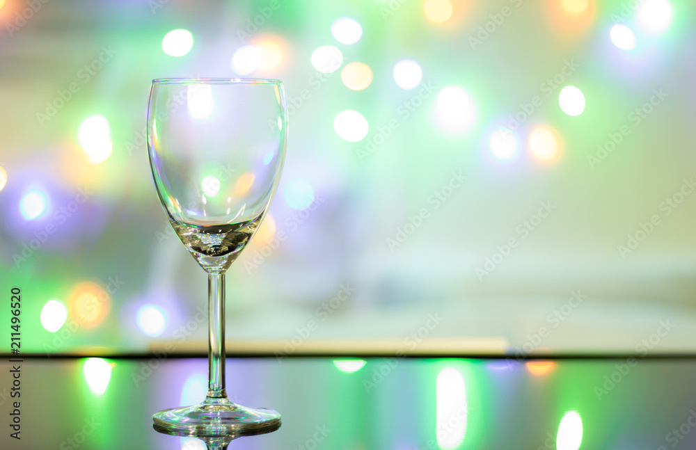 Close up view and copy space. Empty wine glass is on the table and the background is the colorful of sparkling light. Close up view and copy space. Empty wine glass is on the table and the background is the colorful of sparkling light.