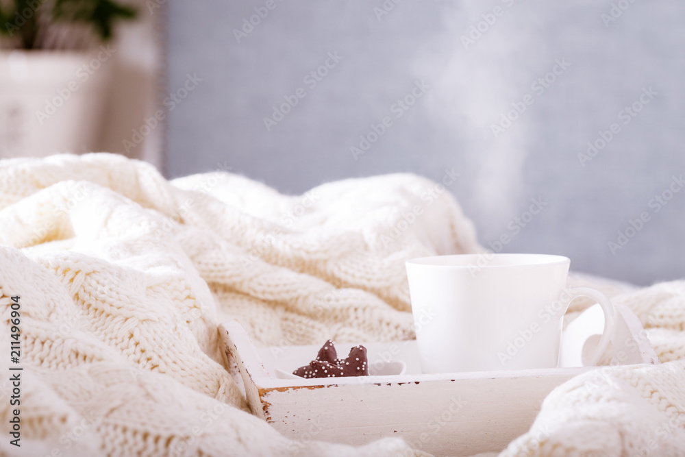 Hot beverage mug with chocolate cookies in a white wool blanket. Hot drink, cozy home and cold season concept Hot beverage mug with chocolate cookies in a white wool blanket. Hot drink, cozy home and cold season concept