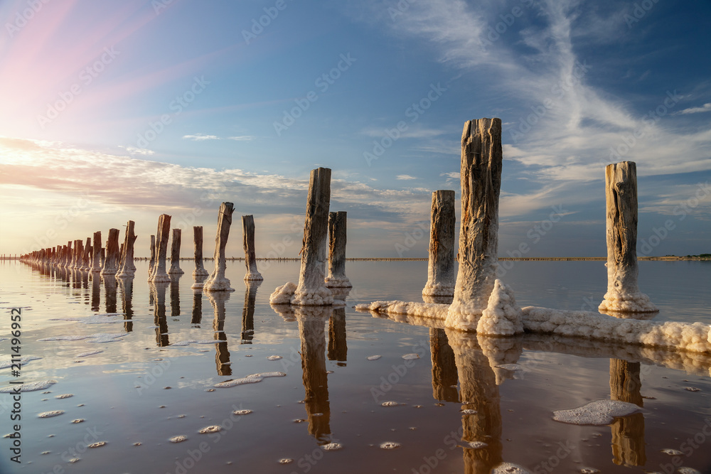 Beautiful sunset or sunrise over a salty lake, Wooden hemp in the build-up of salt after the drying of the lake Beautiful sunset or sunrise over a salty lake, Wooden hemp in the build-up of salt after the drying of the lake
